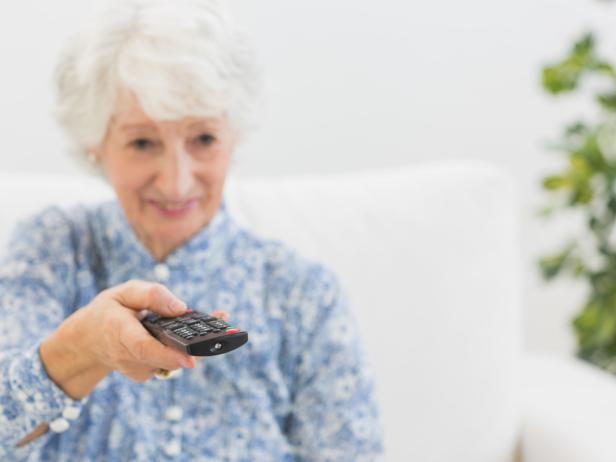 Elderly smiling woman using the remote