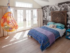 Faded floors and cream walls create a neutral background for this guest bedroom. Global elements and chic black-and-white photo wallpaper bring in a funky, eclectic style.