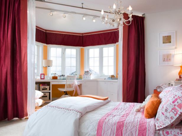 Designer Candice Olson created the ultimate girl's getaway by turning a small bay window into the background for an inspiring workstation and craft area. The white built-in desk unit provides plenty of drawers, cubbies and cabinets for keeping supplies tucked away and out of sight. Dramatic magenta track curtains create an easy separation between workspace and sleep space.