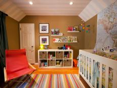 Baby nursery with neutral theme. The parents filed the shelving unit with books and toys. Other items are displayed on picture ledges at varying levels on the wall. The giant map on the wall shows the child they are a citizen of the world.
