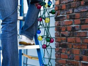 iStock-6894460_woman-hanging-christmas-lights-outside-from-ladder_s3x4