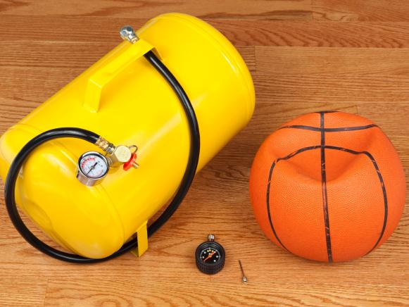 Flat basketball with portable air tank, pressure gauge, and needle valve for filling the ball.