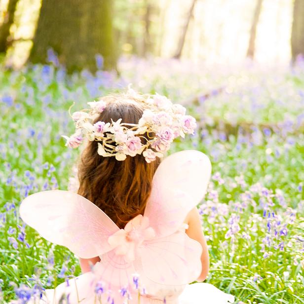Fairy Princess in a sea of Bluebells deep in the woods.  Floral headdress and backlit by sunlight.
