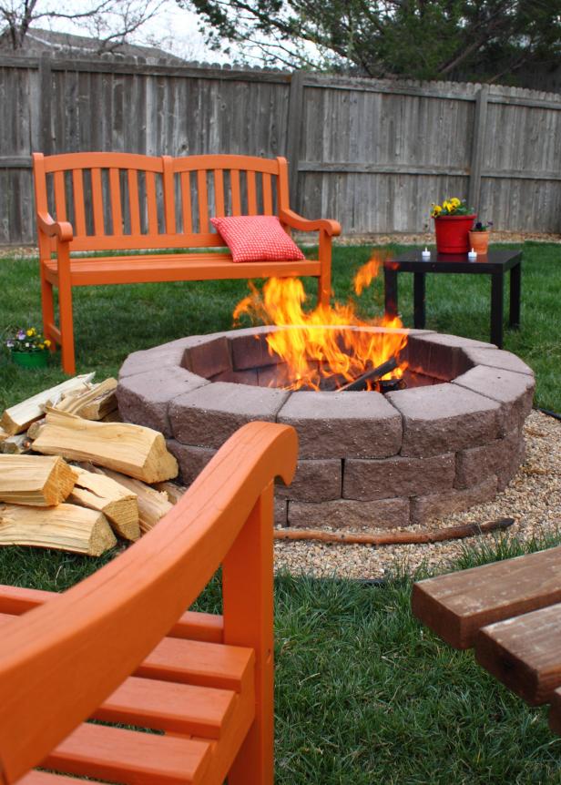 This charming back yard fire pit is surrounded by brightly colored orange chairs and benches.