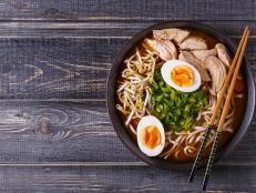 Japanese ramen soup with chicken, egg, chives and sprout on dark wooden background.