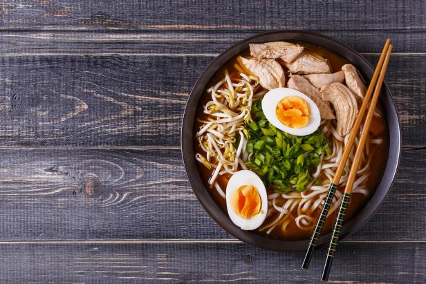 Japanese ramen soup with chicken, egg, chives and sprout on dark wooden background.