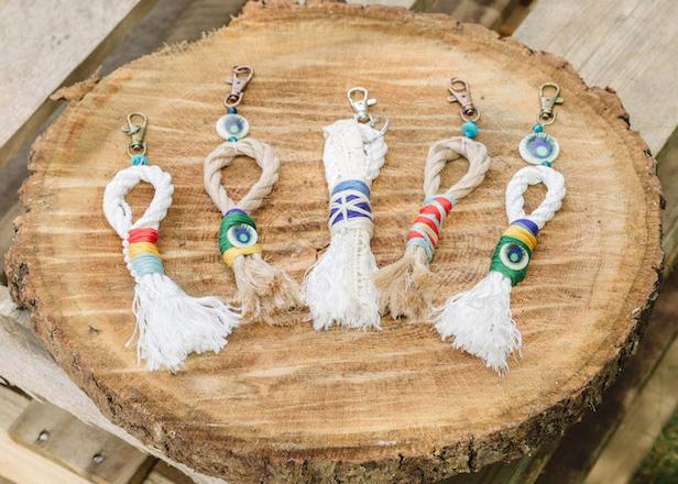 Step 1: Cut a 5-inch piece of twine or string, then tie a knot around the jump ring. 
Step 2: Choose 2-5 beads and add them to the twine. Set aside. 
Step 3: Use scissors to cut a 10-inch piece of cotton rope.
Step 4: Pull apart the two ends of the rope to create frayed edges, then overlap to form a loop.
Step 5: Use tape to keep the loop in place, then glue to secure it.
Step 6: Select your first color of thread. Wrap the thread tightly across the entire loop, using  glue to secure it as you go. Let that thread dry, then continue with your next color. 
Step 7: When complete, use your previous piece of twine to attach the tassel to the end of your        keychain. 
Bonus Step: Tie craft ribbon to your jump ring for a more festive look.