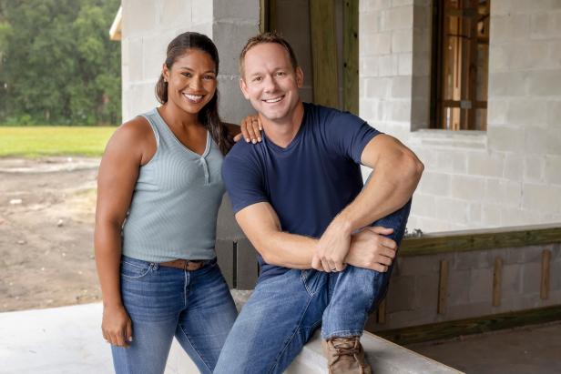 Hosts Brian and Mika Kleinschmidt pose in front of the block wall construction site , as seen on HGTV's 100 Day Dream Home, Season 3.