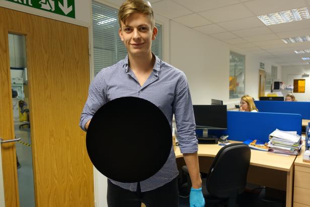 A scientist holding a 3D object coated in Vantablack paint.