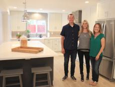 Host Christina Anstead (right) and clients Jamie and Travis (left) stand in their Fountain Valley, CA kitchen after Jamie and Travis' first look at their new space, as seen on HGTV's Christina on the Coast.