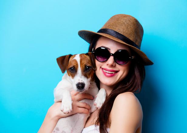 portrait of the beautiful young woman with dog on the blue background