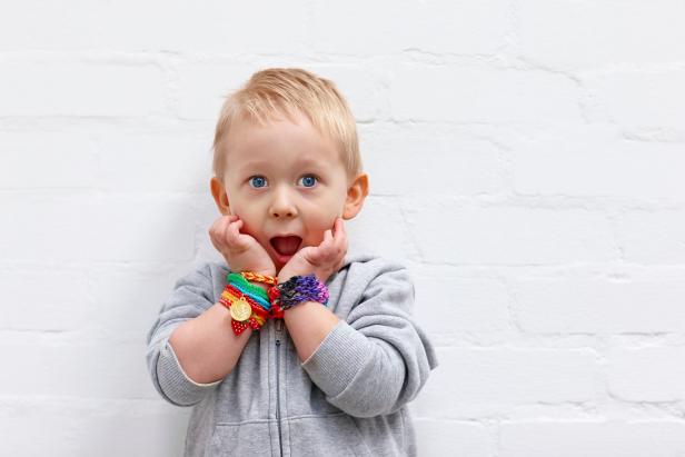 Portrait of cute little boy wearing colorful loom bands looking surprised