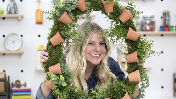 HGTV stylist Jill Tennant poses with a spring wreath made from a grapevine wreath, terra-cotta pots and faux greenery.