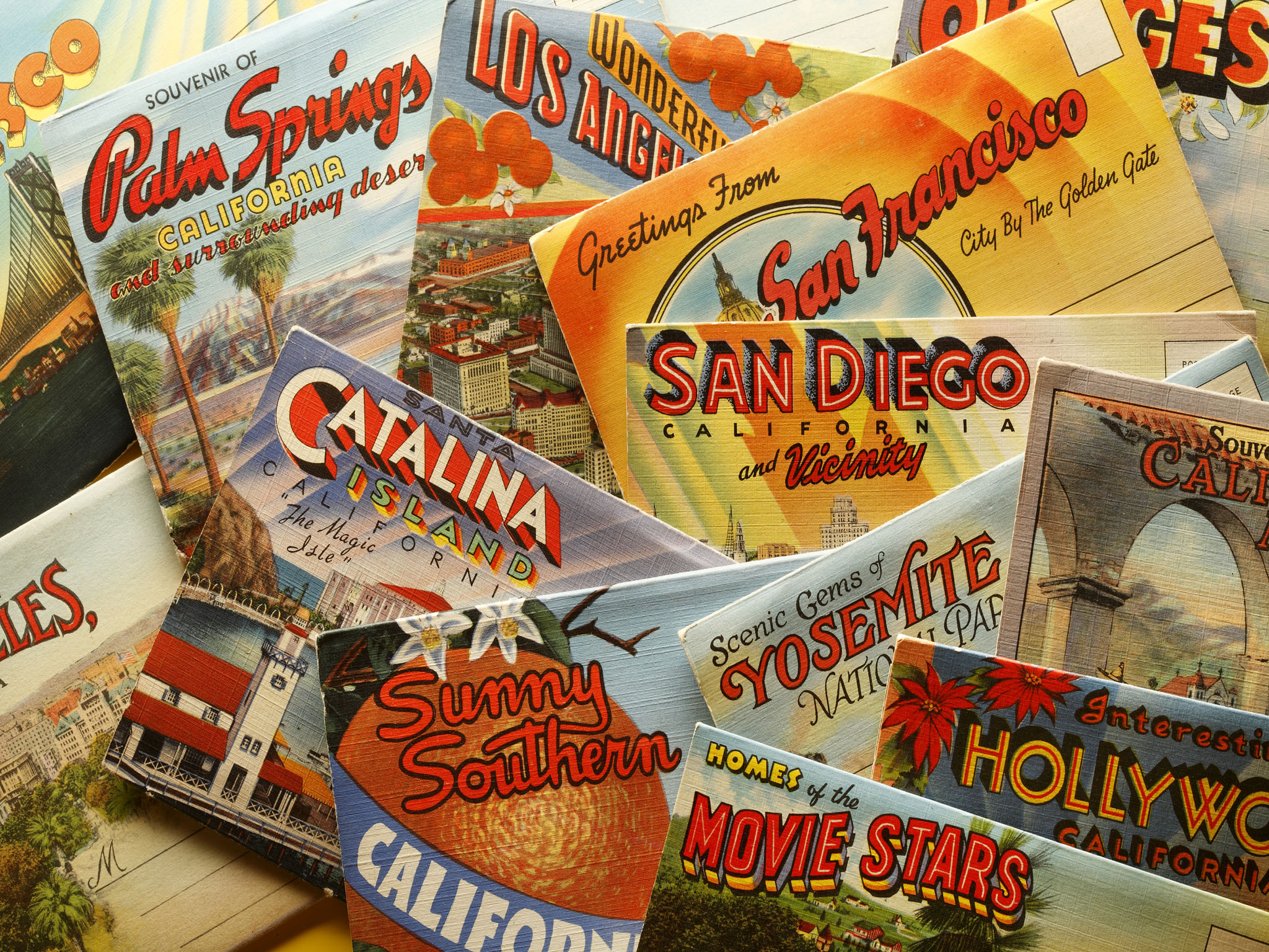 San Diego, California, USA - November 8, 2013: A group of vintage postcards showing various California tourist destinations. Shot in a studio setting on a yellow background.