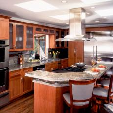Wood Kitchen Cabinets With Frosted Glass Doors, Granite Countertop Over Curved Eat In Bar and Leather Upholstered Bar Chairs