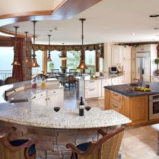 Spacious, Open Design Kitchen With Textured Rock Curved Bar, Light Neutral Granite Countertop and Traditional Pendant Lights