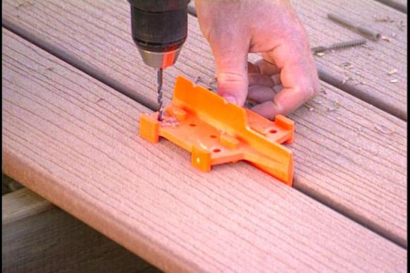 Man using a deck guide to align holes for drilling.