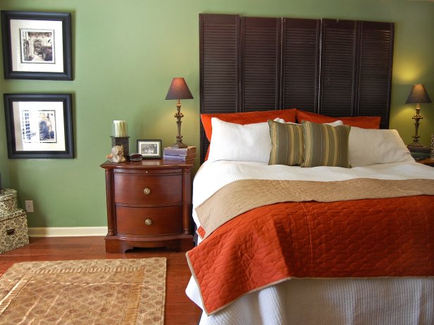 Green Walls in a Bedroom with Orange Bed Linen. 