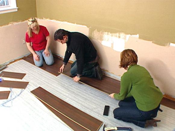 Three People Laying Floor Boards 