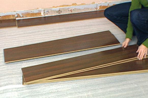 Woman laying laminate boards over barrier 