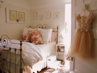 A white bedroom with pink floral pillows. 