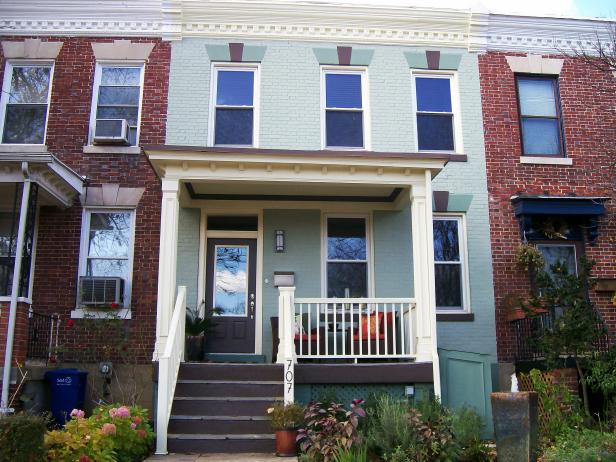 Blue Brick House With White Porch Railing and Gray Stairs