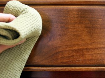 Wiping down a kitchen cabinet once it is sanded.