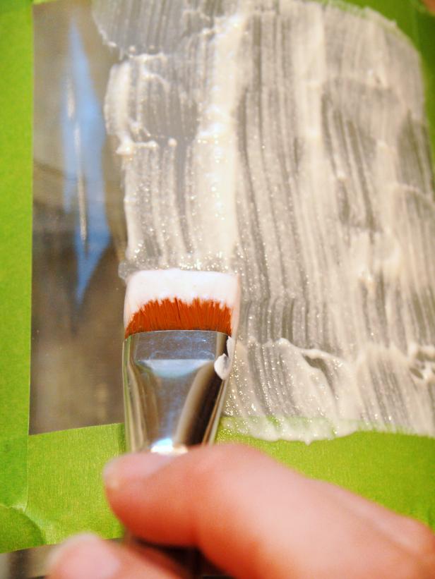 Applying etching cream with a brush to prepare for chalkboard paint. 