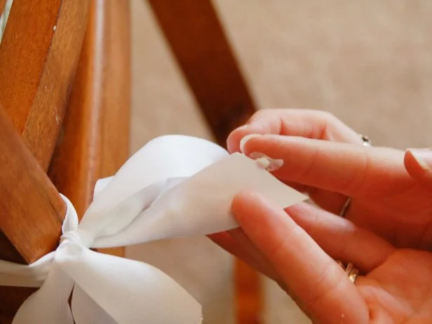 After removing pins and trimming threads, Step 7B in creating a barstool cover is to run a bead of fabric glue along edge of the twill tape ties to prevent fraying.