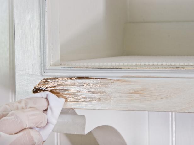 Glazing a kitchen cabinet with antiquing glaze using a rag.