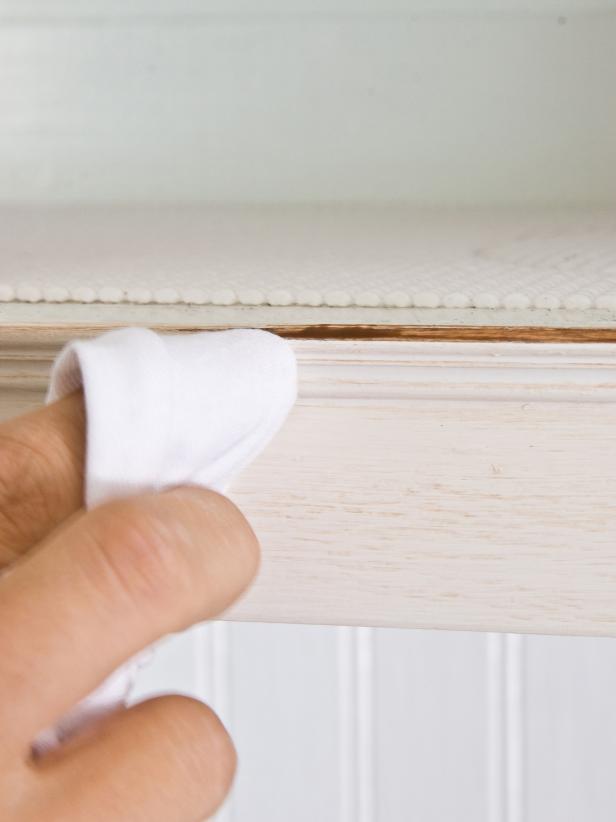 Wiping off excess glaze from a cabinet with a soft cloth. 