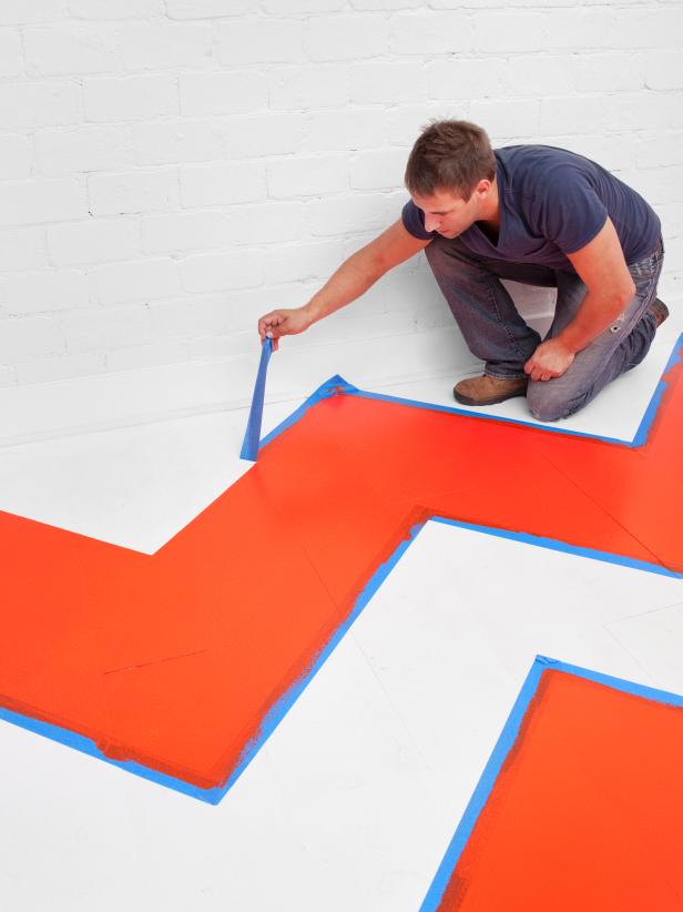 Man removing painters tape from the floor. 