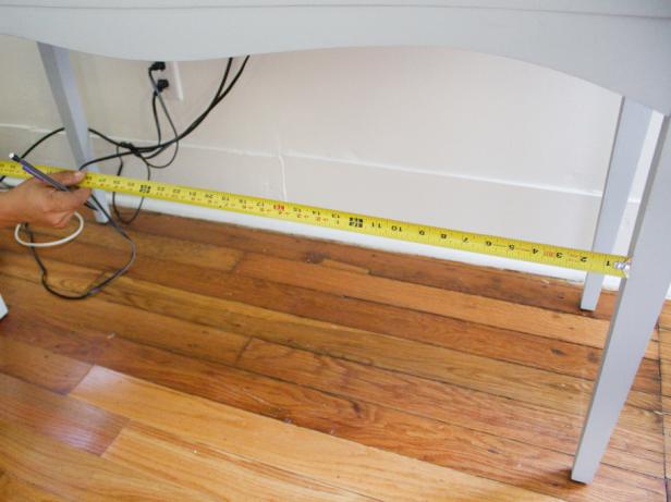 Man measuring a sideboard to install shelving. 