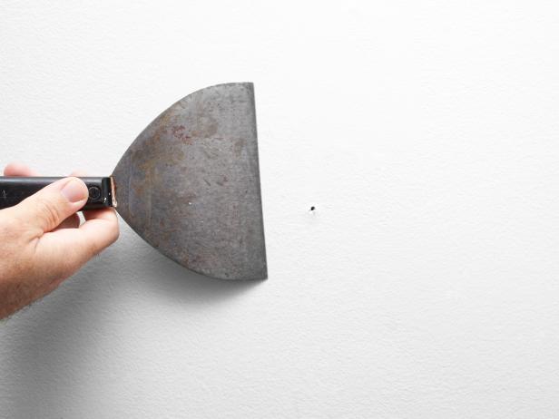 Comb wall surface with spackle knife to loosen up paint build-up or bumps. Fill nail holes with spackle and spackle knife. Once spackle has dried, sand with sanding block. Wipe entire wall with sponge dipped in warm water.