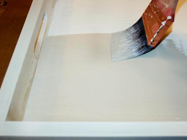 White wooden tray being painted gray. 