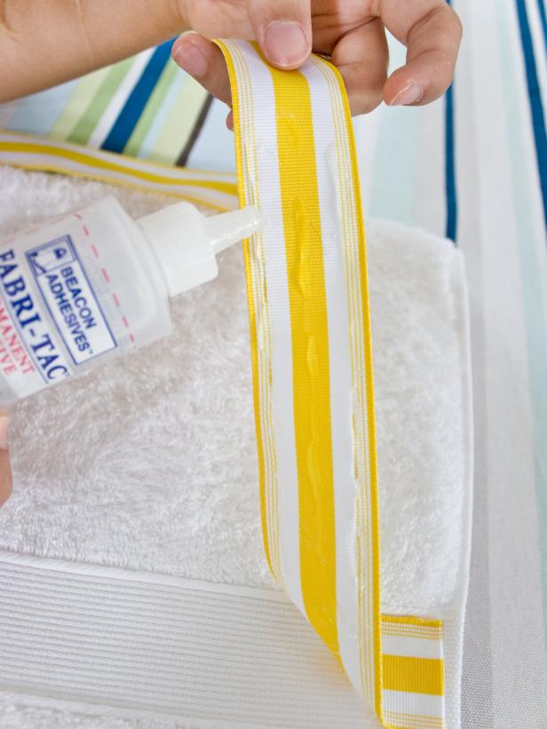 Hand Adding Fabric Glue to Yellow & White Striped Ribbon