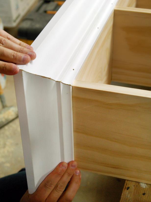 To attach crown molding, line up mitered edges perfectly and hold bottom of crown molding flush with top edge of shelving unit.