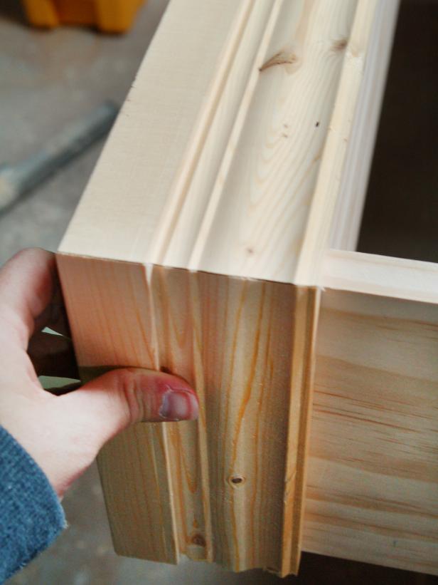 To attach the base molding, make sure that the top of the molding is flush with the top of the bottom shelf and repeat process around the bottom of the shelving unit.