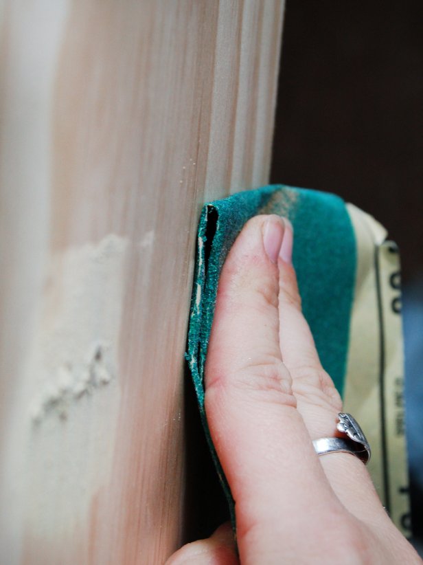 Hand Using Folded Sand Paper to Sand Wood Surface