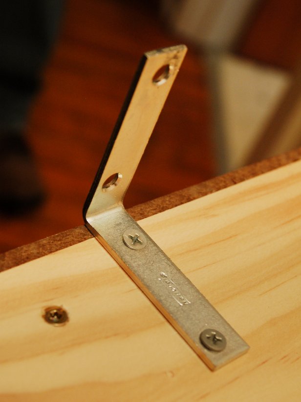 Install the L bracket on top of the cabinet. Place the cabinet on the wall, resting on the cleat, and screw the L bracket into wall. Tack a few nails through the bottom shelf into the cleat to hold the shelf securely in place. Fill with baskets and toiletries. Tip: If installing in drywall, locate a stud for optimal placement. If stud placement doesn't line up with shelf placement, use wall anchors.