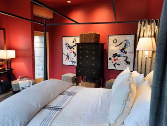 Red bedroom with a canopy bed and modern art.