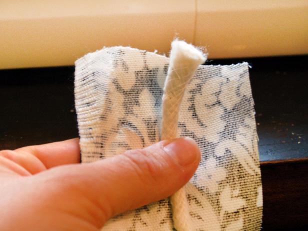 Cut cotton piping cord to sink width, plus 1 inch for seam allowance. Measure and cut a piece of fabric that's 2 inches wide and the length of the sink width plus 1 inch. (<b>Example:</b> If sink width is 30 inches, the fabric piece would measure 31 inches by 2 inches.)