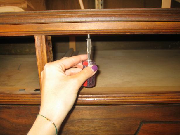 Unscrewing Top of Wood Dresser With Screwdriver 