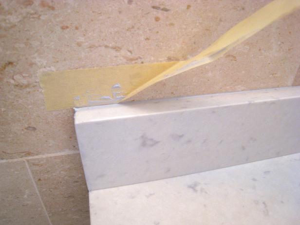 Carefully remove tape used to protect wall above where backsplash was installed. Using tape keeps caulk, paint and other project materials from staining the wall.