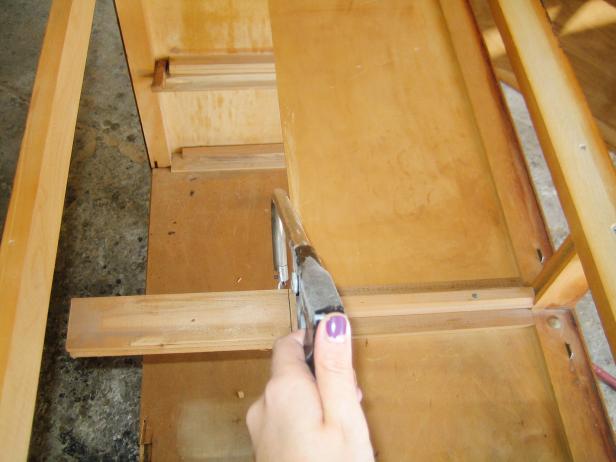 Remove the support beam that runs parallel to the bottom of the cabinet by sawing off about six inches.