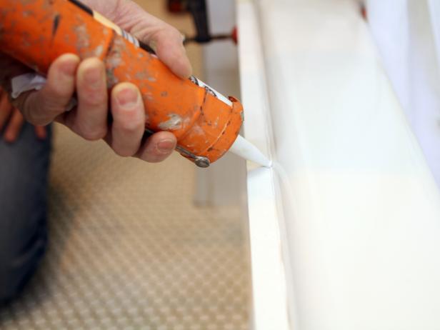 Apply silicone adhesive directly to front of tub using caulk gun. Press panel into place, then add clamps.