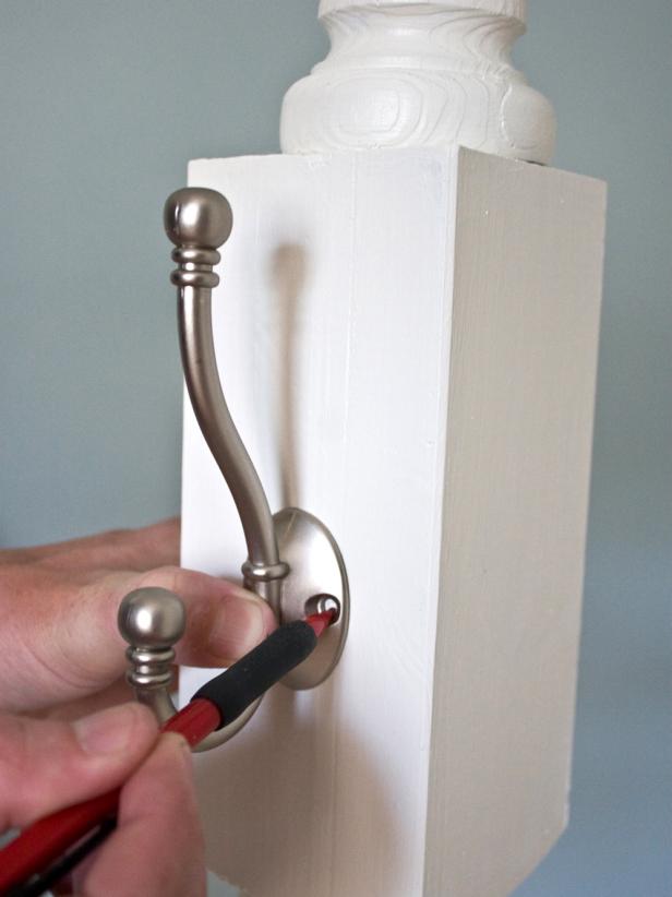 Using a pencil, make marks on the post where each coat hook should be attached. Use a drill bit slightly smaller than the size of the screws included with the coat hooks to pre-drill holes.