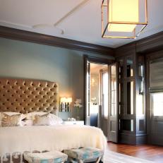 Bedroom With Gold Upholstered Headboard and Geometric Light Fixture