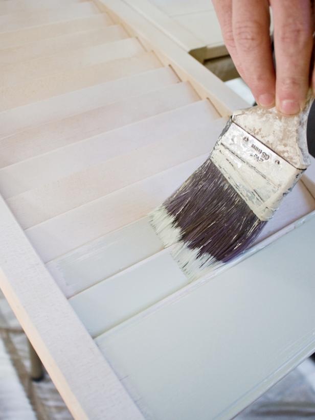 Once the primer has completely dried, use a 2-inch wide paintbrush to coat the shutters with paint. To create a weathered look, load the brush with paint; then wipe some of it off onto a paper towel before applying it to the shutters — this technique is called &quot;dry brushing&quot; and allows some of the primer and wood color to show through.