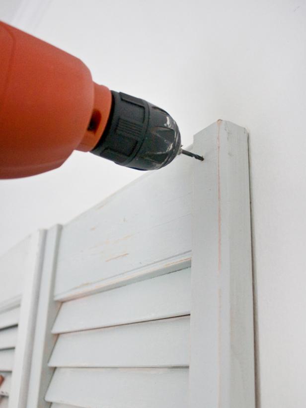 Power Drill Drilling Hole Through White Shutter Headboard and Wall